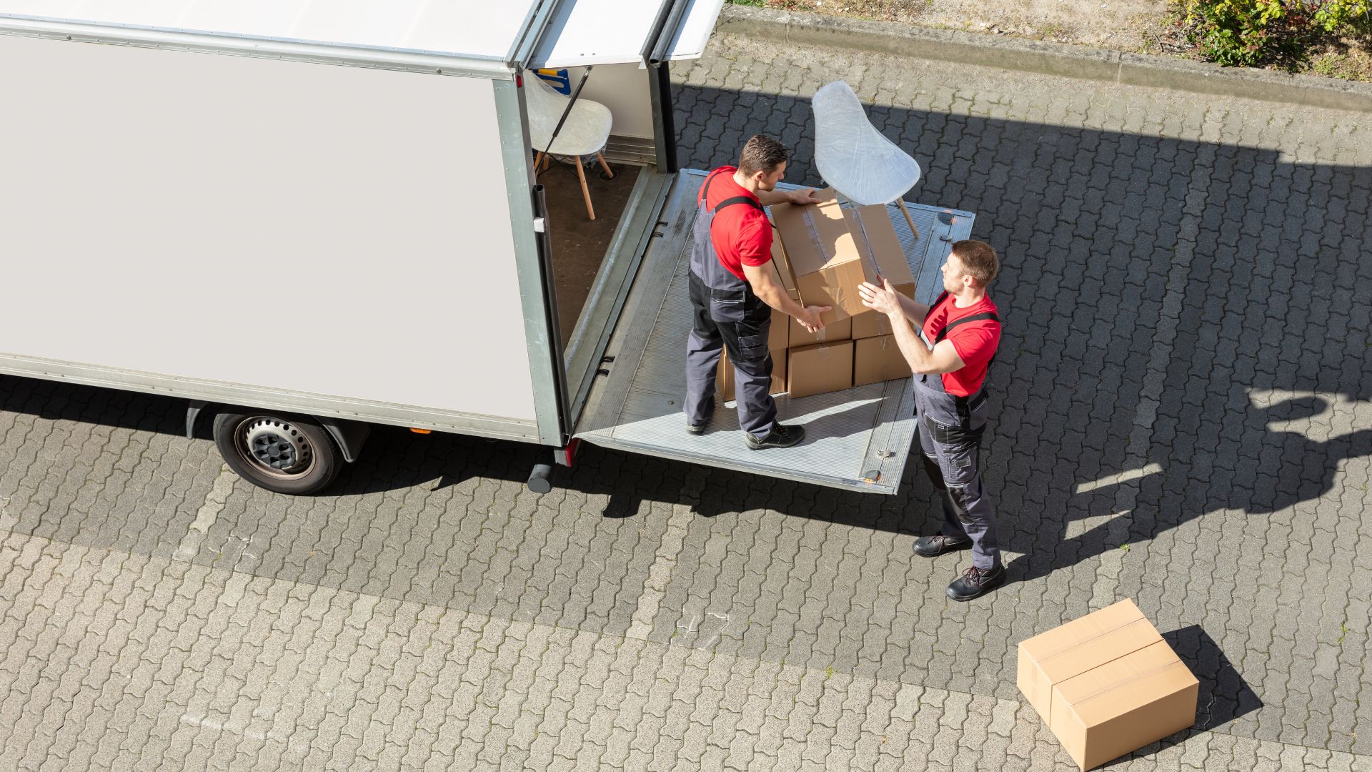 Two men unloading boxes from a moving truck